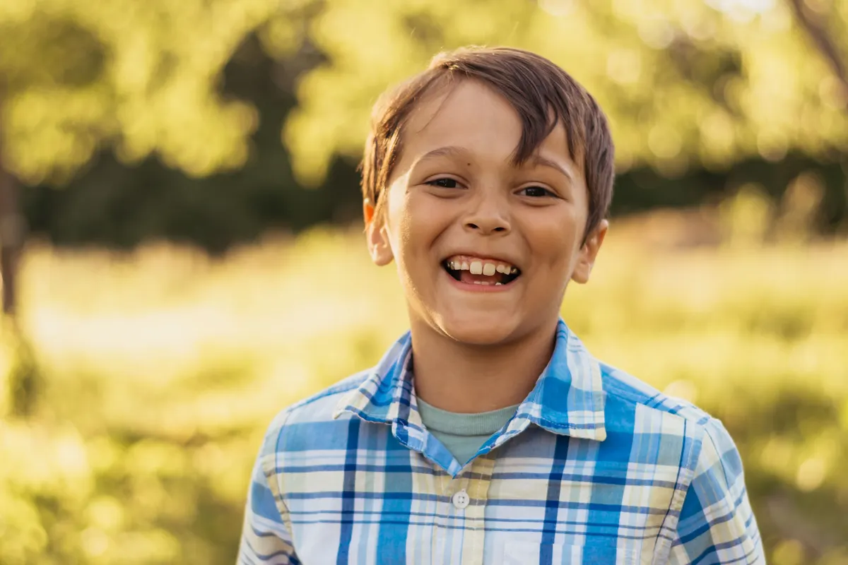 Boy laughing in a plaid shirt at golden hour