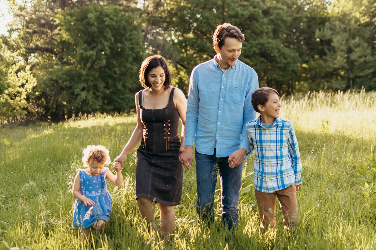 Family of four walking hand in hand through a South Hills meadow at golden hour