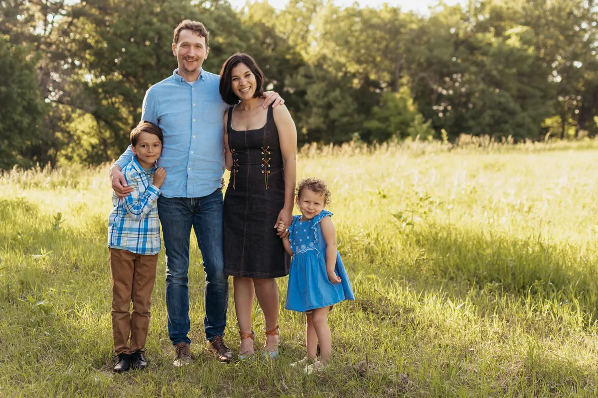 Family of four standing together in a South Park meadow at golden hour