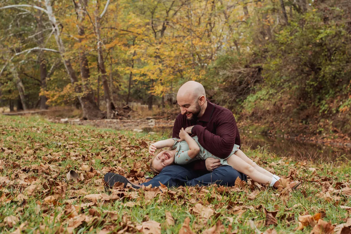 Dad playing with his child in a pile of fall leaves