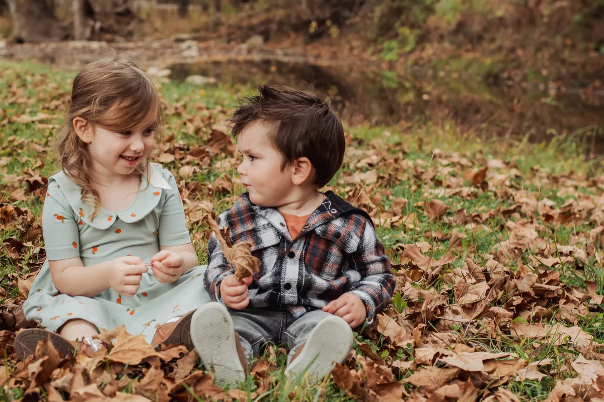 Two toddlers playing in fall leaves during a family session