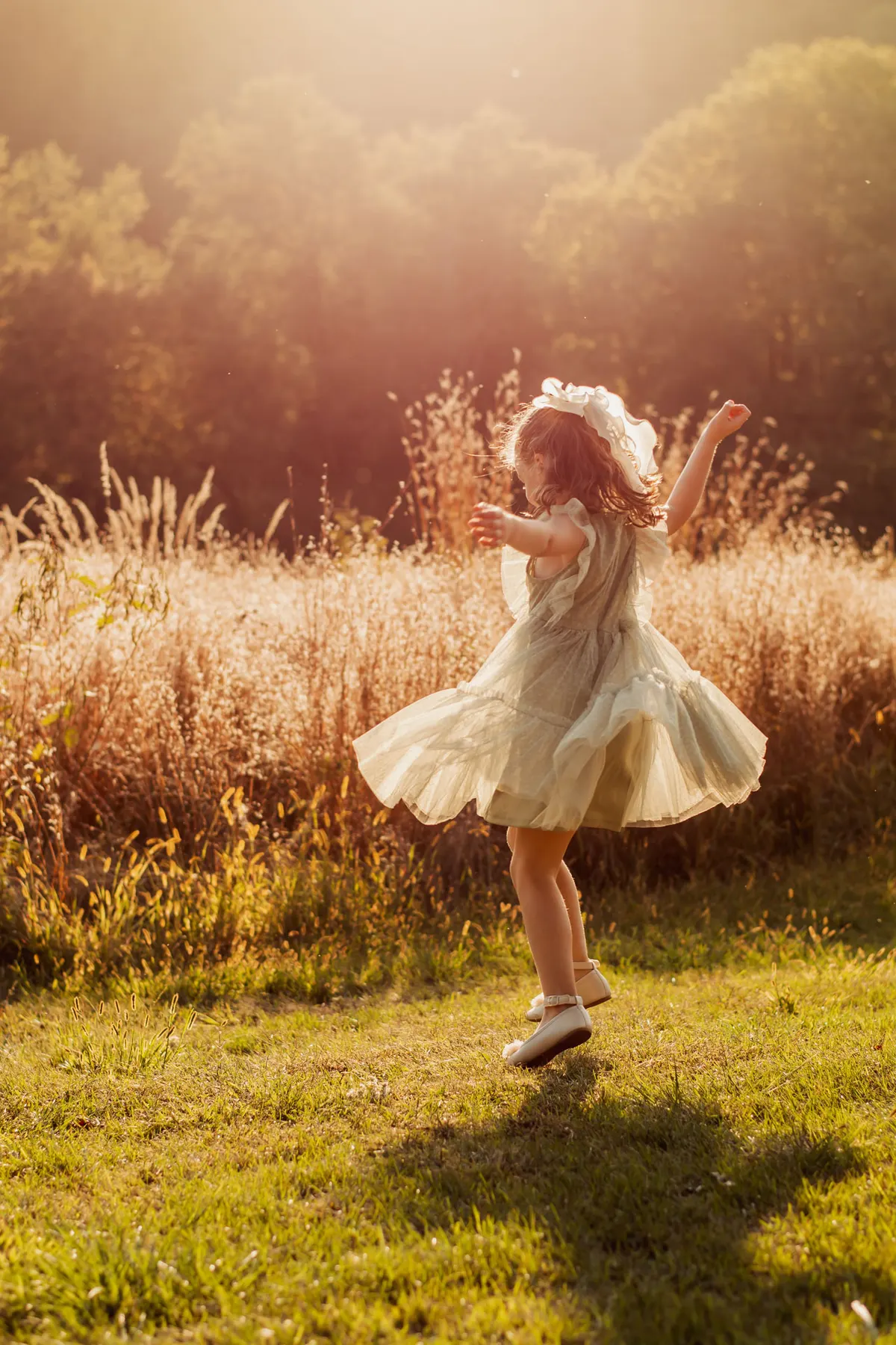 Little girl twirling in a sunlit field at South Park