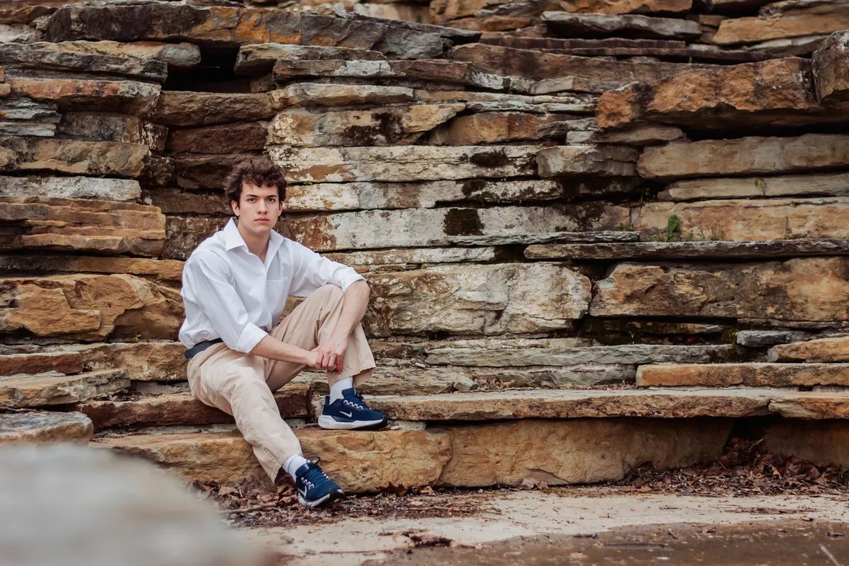 Senior boy sitting against the layered stone of the South Park cascades
