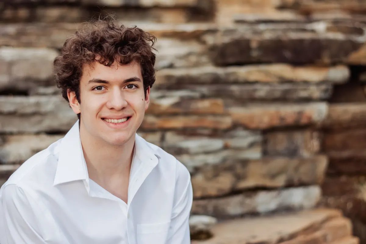 Close-up of a smiling senior boy against layered stone at South Park