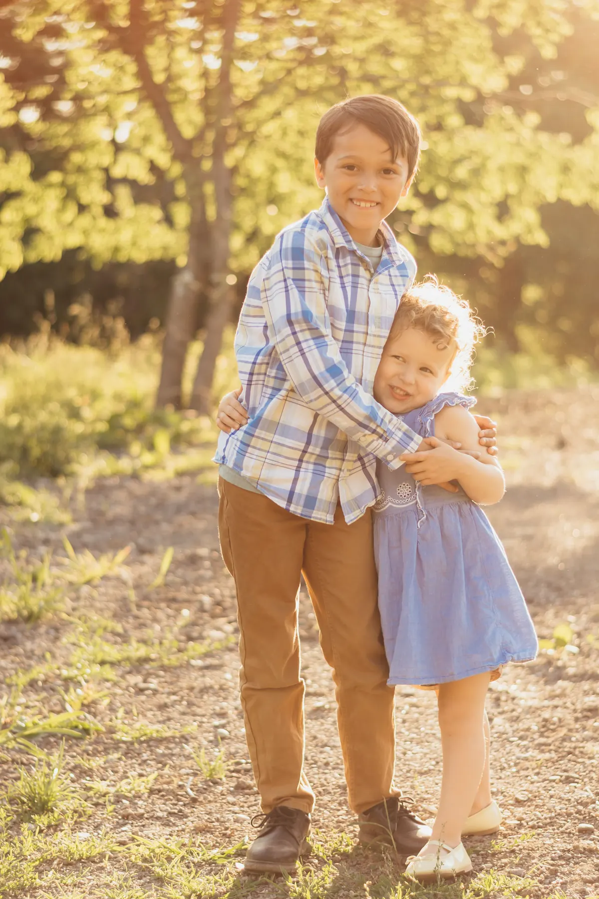 Big brother hugging his little sister in golden evening light