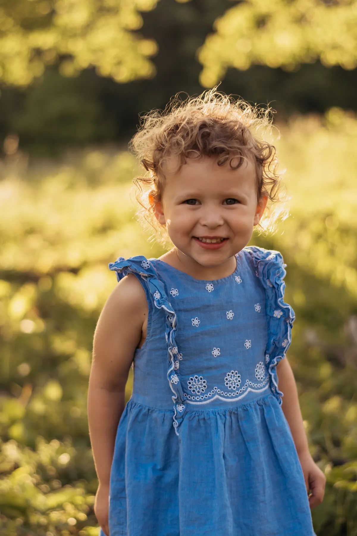Close-up portrait of a curly-haired toddler girl at golden hour